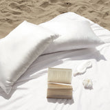 Set of two Silk Works ivory mulberry silk pillowcases on the beach with a pure silk eye mask.