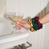 Hand holding a cocktail glass with colorful scrunchies on a white surface