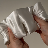 Cloud ivory silk eye mask being gently squished in hand – showing softness, padded texture, and premium quality mulberry silk
