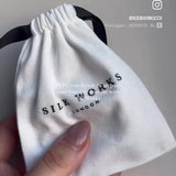 User-generated video showing close-up unboxing of Silk Works packaging, revealing a set of three charcoal grey skinny silk scrunchies and a grey 22 momme Silk Works pillowcase—highlighting texture, detail, and luxury presentation.
