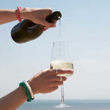 Mulberry silk scrunchies on wrist pouring champagne by the sea