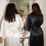 Two women in silk robes standing in a bathroom.