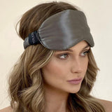 Model wearing a Silk Works charcoal grey mulberry silk eye mask with a soft ruched strap, styled with loose waves and a natural makeup look