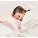 Child peacefully sleeping on a blush pink Silk Works mulberry silk pillowcase, shown in a cosy bedroom setting.