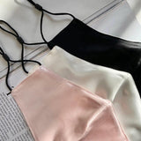 Set of three Silk Works mulberry silk face masks in blush pink, ivory, and black with adjustable ear loops, displayed on an open magazine.