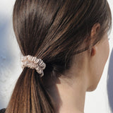 Woman wearing a skinny caramel mulberry silk scrunchie in her hair – soft, elegant, and perfect for a gentle, crease-free hold.