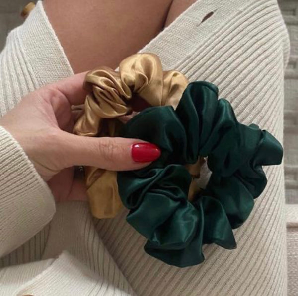 Lady holding a large green and gold mulberry silk scrunchie.