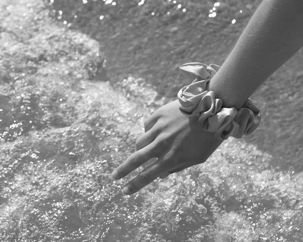 black and white image girl wears silk scrunchie on wrist by the ocean