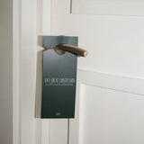 Door handle with a 'Do Not Disturb' sign attached to a white door.
