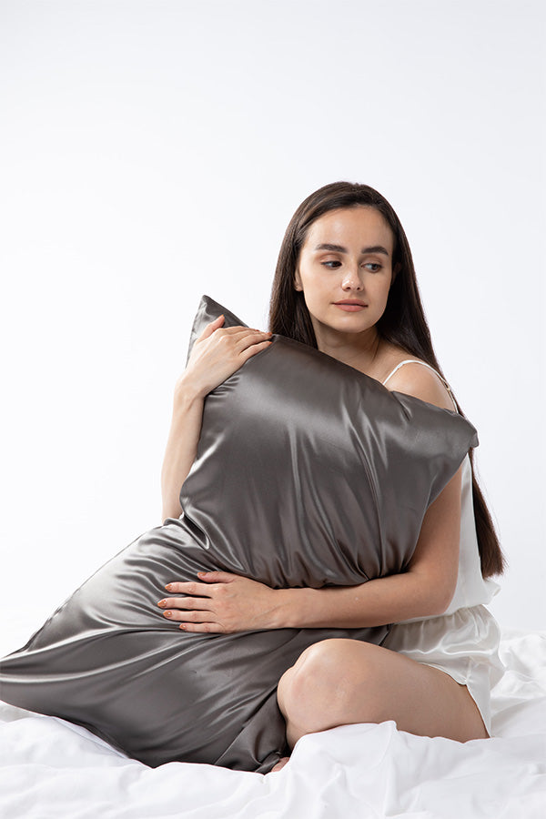 Lady holding a grey silk pillowcase while sitting in bed