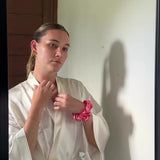 Video clip of a lady tying her hair in a bun with a large watermelon coloured silk scrunchie.