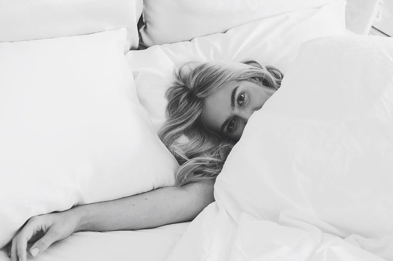 Model lying on two ivory white pure mulberry silk pillowcases by Silk Works London UK