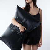 lady wearing black silk shorts and camisole holding black mulberry silk pillowcase